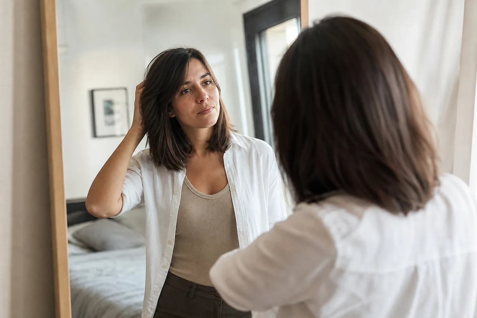 Mujer adulta observa su nuevo corte frente al espejo en un cambio de look después de una ruptura, una transformación serena para ZOE Salon Guatemala