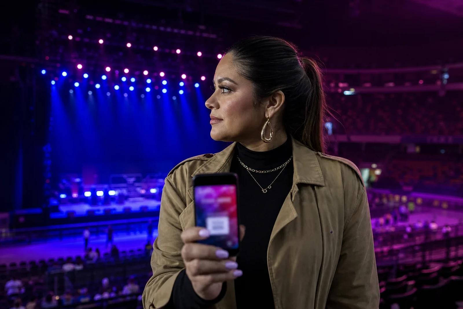Mujer revisa su entrada ante un escenario vacío mientras espera el concierto de Cazzu Guatemala, imagen editorial para ZOE Salon Guatemala.