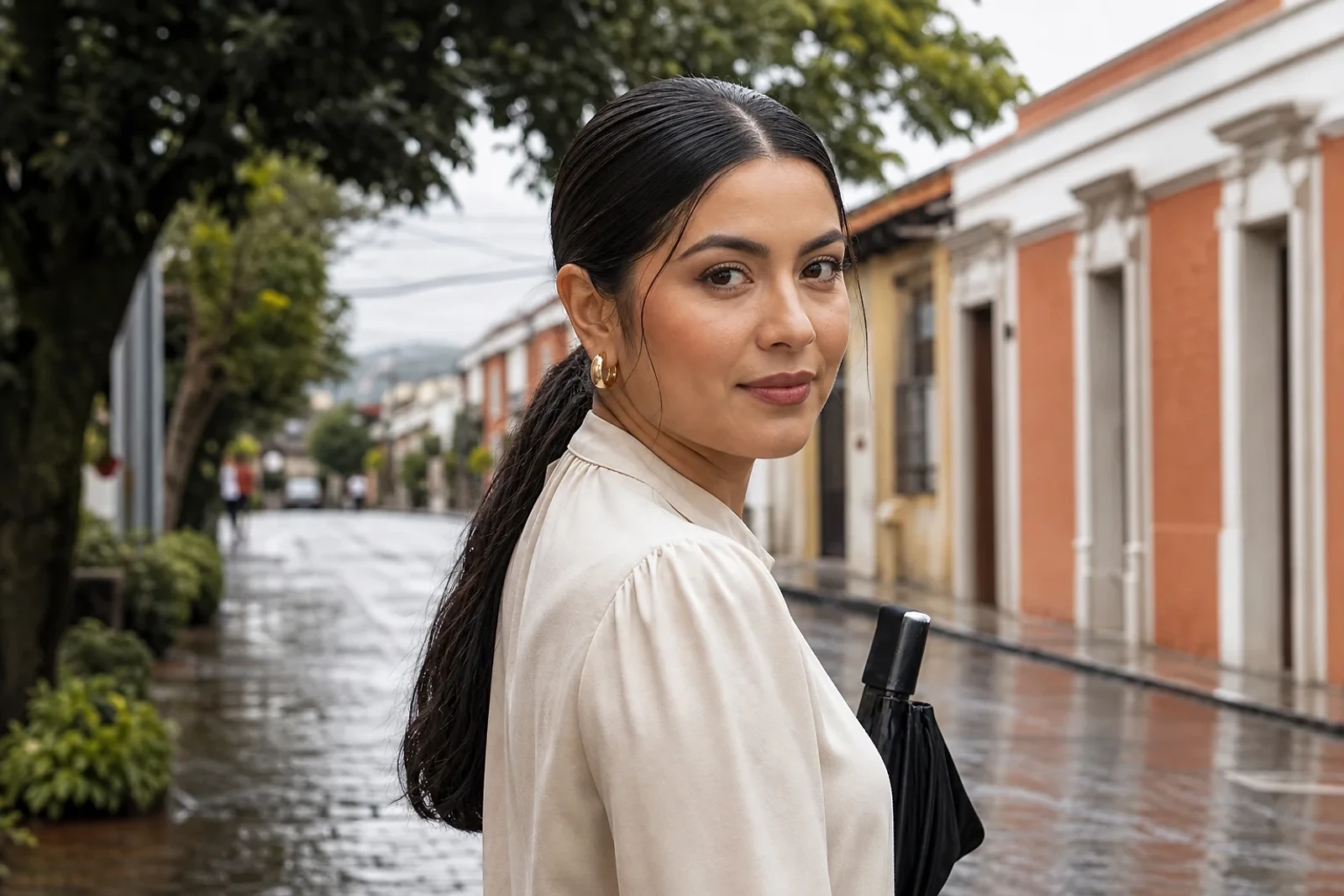 Mujer con coleta baja pulida frente a una calle mojada, ejemplo de Peinados para lluvia y humedad en Guatemala para días activos